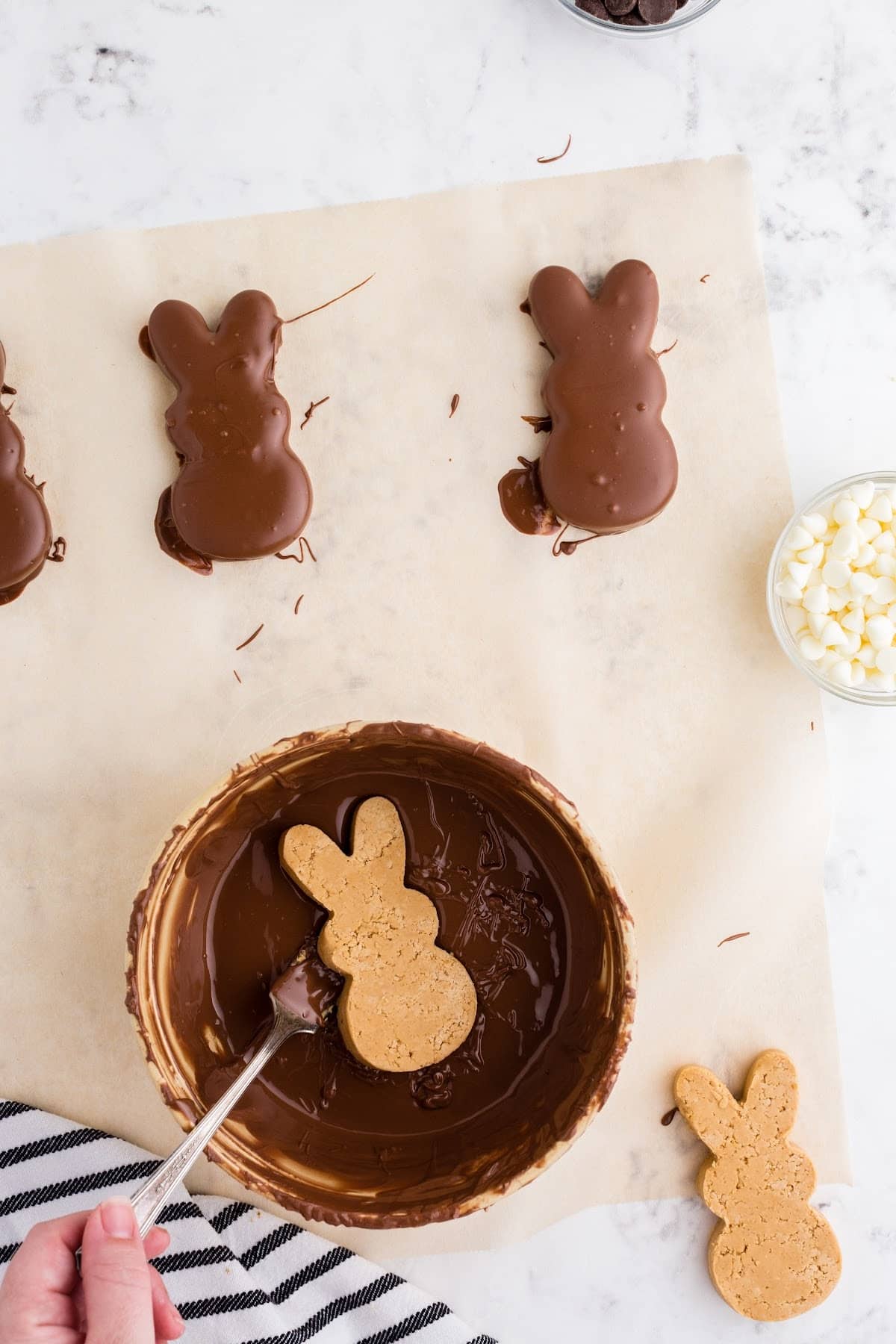 Dipping the cut out bunnies into the melted chocolate, with covered bunnies off to the side, hardening.
