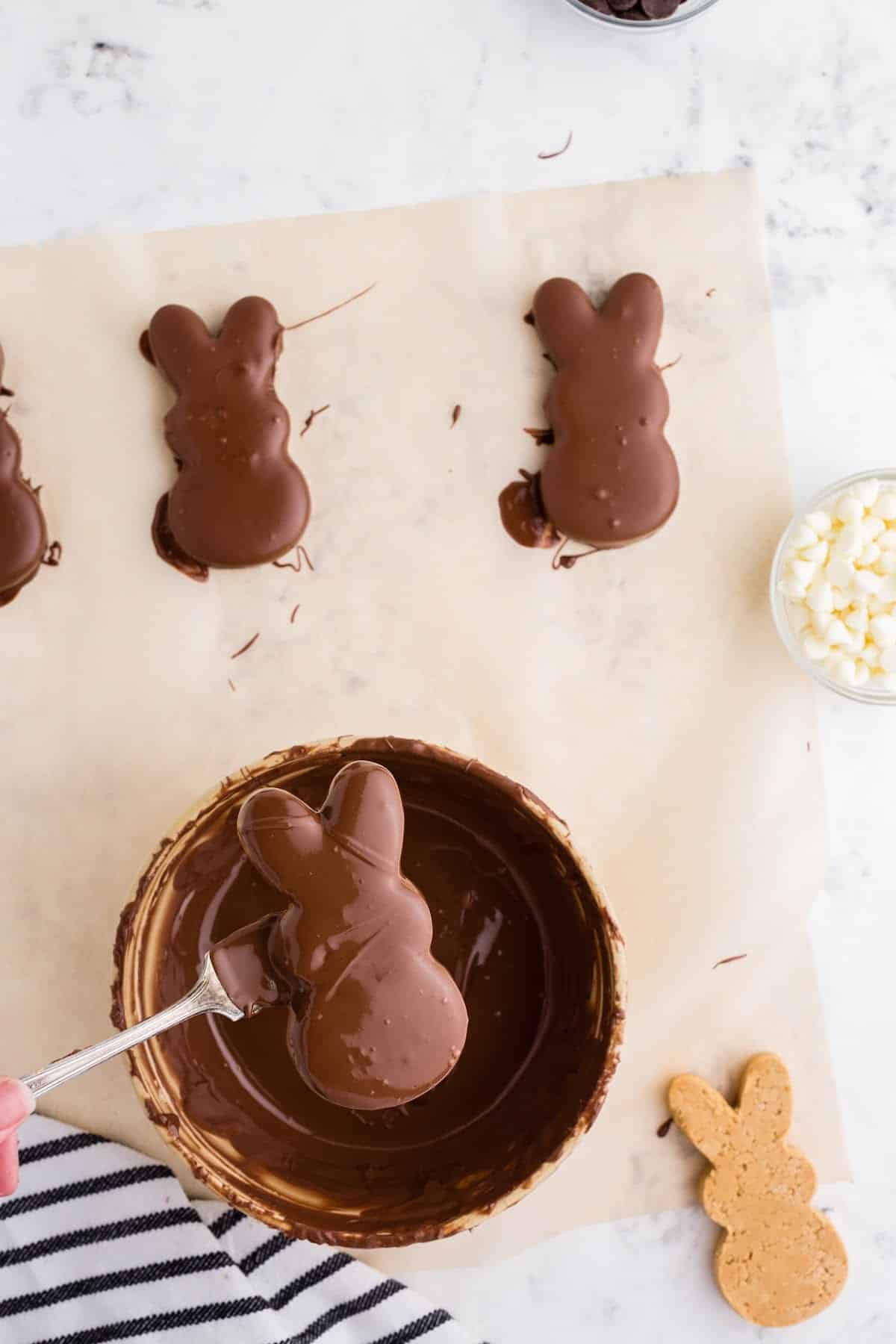 Dipping the cut out bunnies into the melted chocolate, with covered bunnies off to the side, hardening.