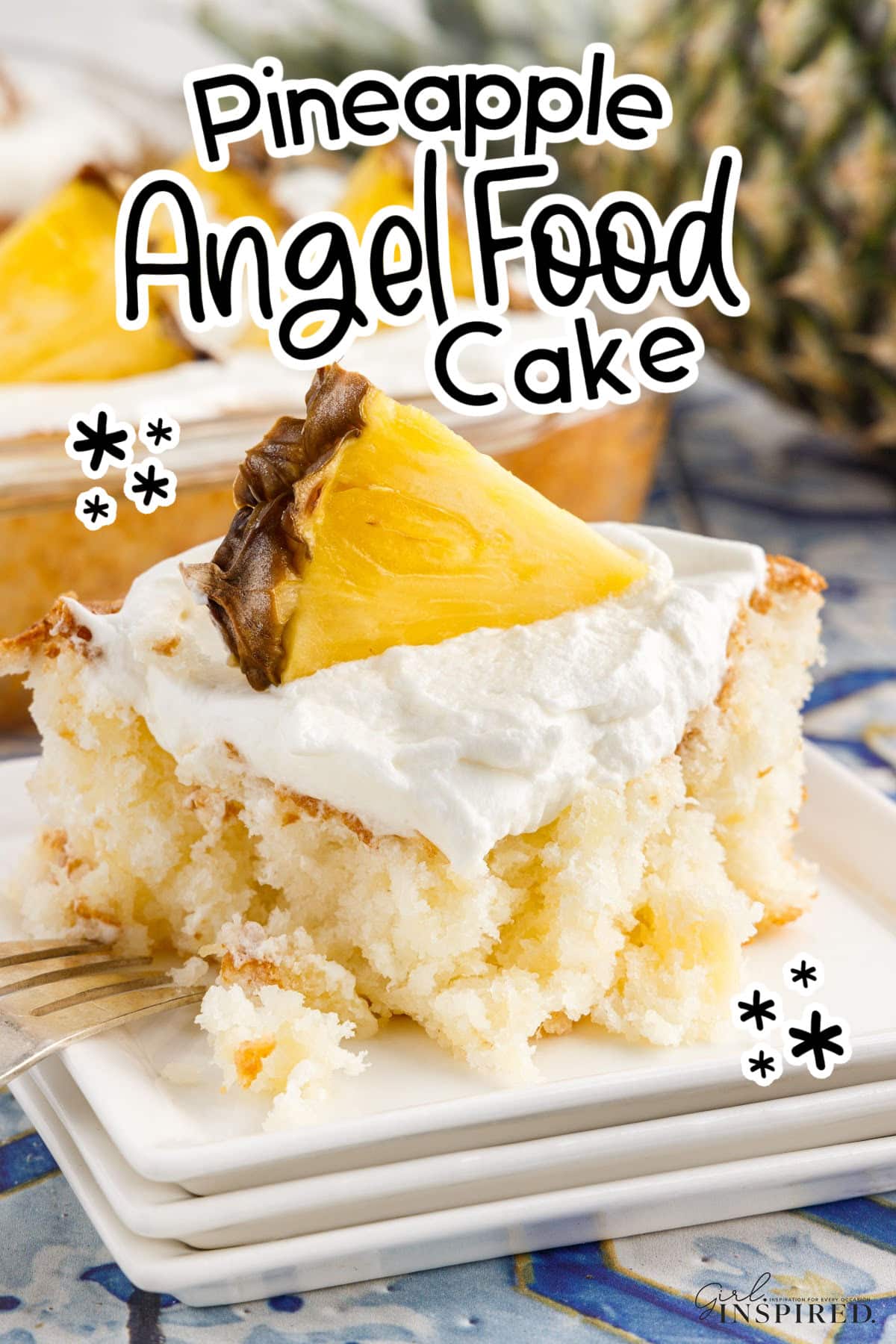 Slice of Pineapple Angel Food Cake on a plate with a garnish of frosting and a slice if pineapple on top, with text overlay.
