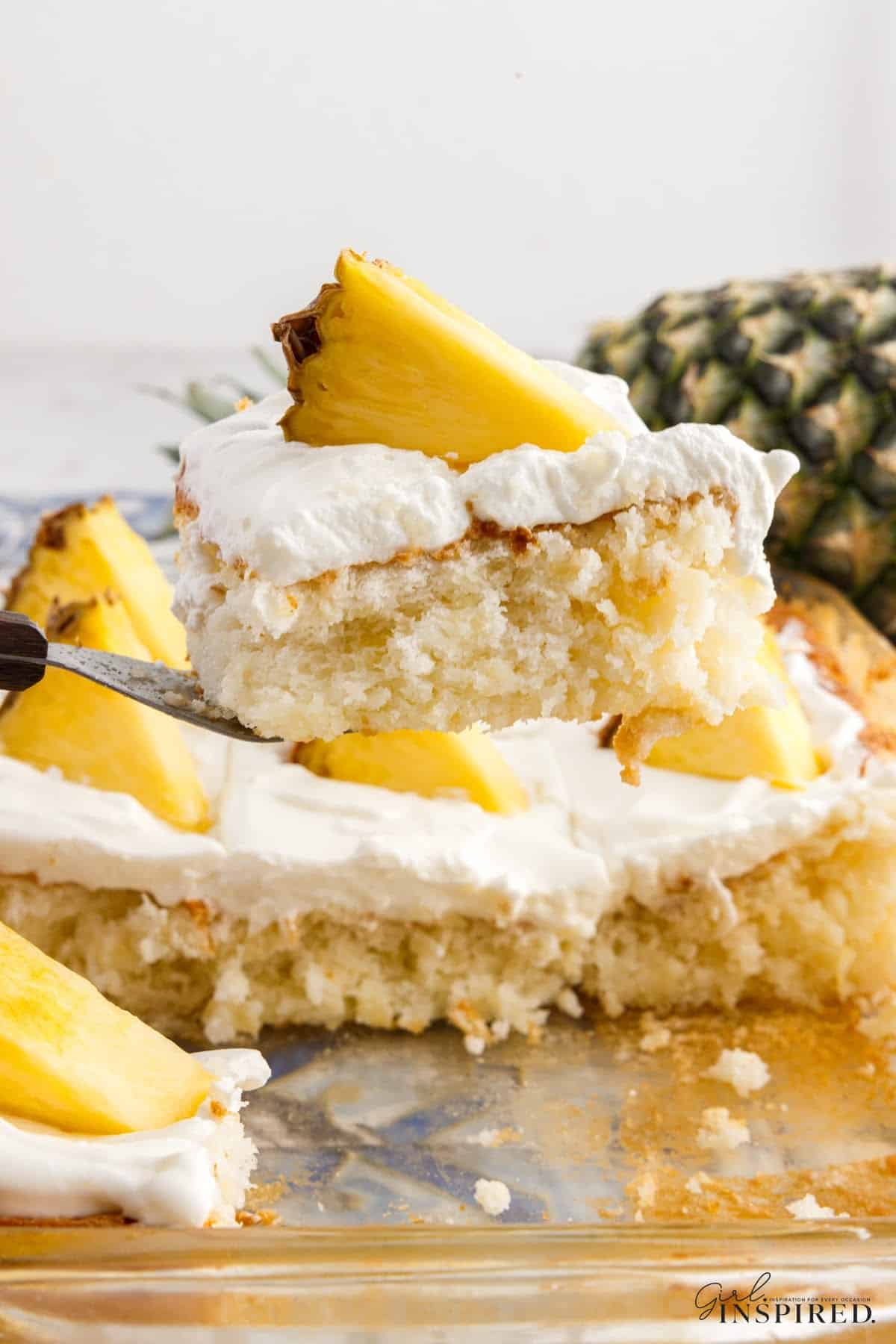 Slice of Pineapple Angel Food Cake on a plate with a garnish of frosting and a slice if pineapple on top, with text overlay.