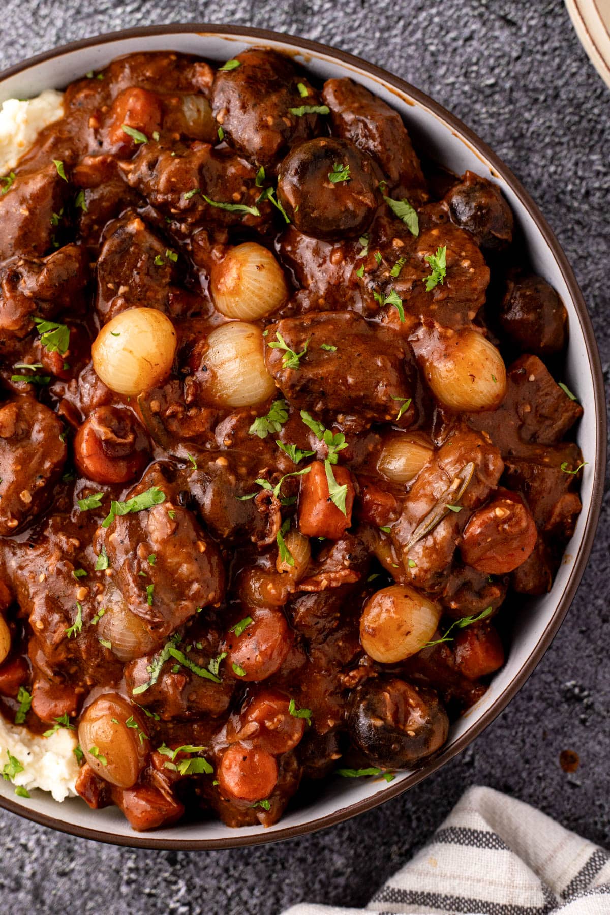 Beef bourguignon over mashed potatoes in serving bowl.