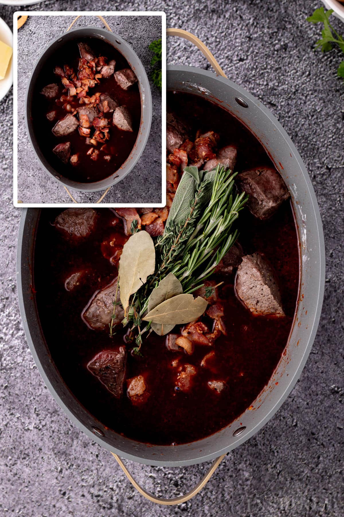 Browned meat and bacon, fresh herbs mounded in stock pot with other beef bourguignon ingredients.