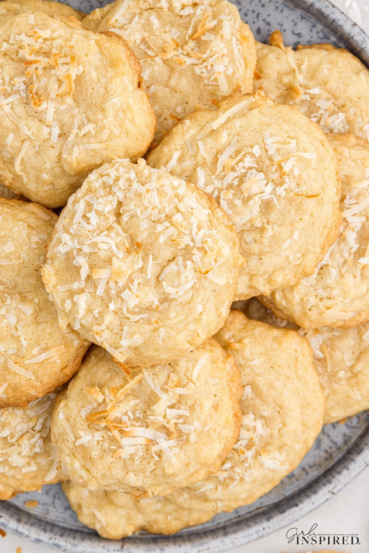Pile of Chewy Coconut Cookies on a platter, showing the coconut flakes on top.