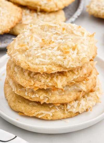 Stack of Chewy Coconut Cookies showing the flakes on the outside of the cookie, with text overlays.