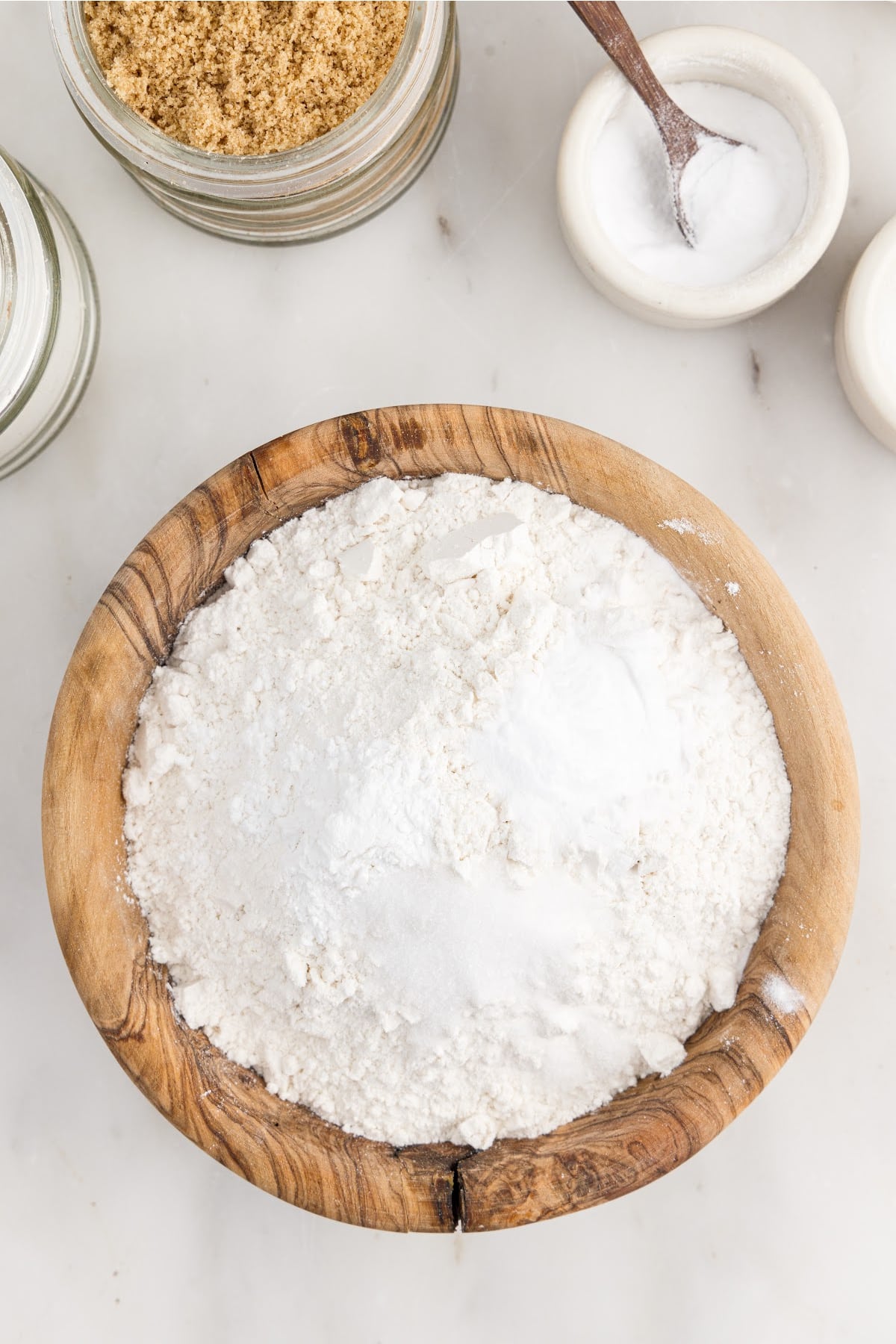 Mixing the dry ingredients together in a bowl, with other ingredients in the background.