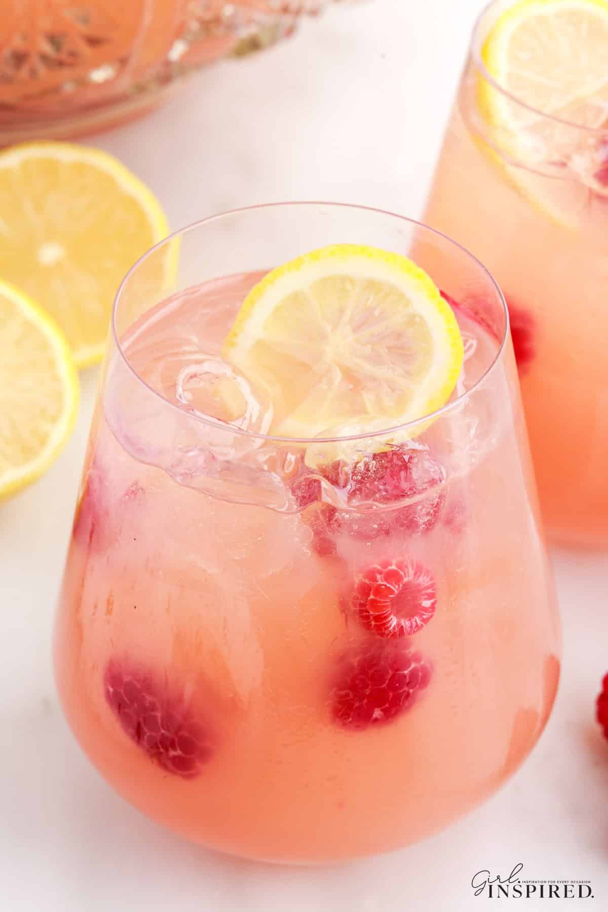 Glass filled with Party Punch, garnished with a slice of lemon and berries, lemons in the background.