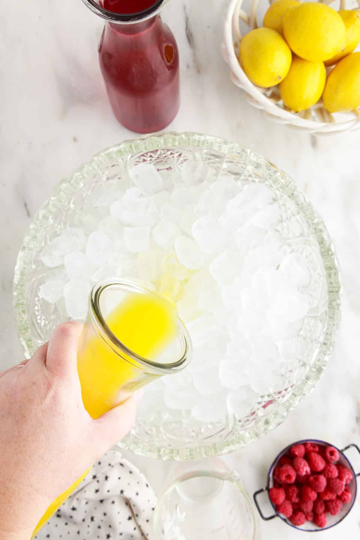 Adding the orange juice to the bowl of ice.
