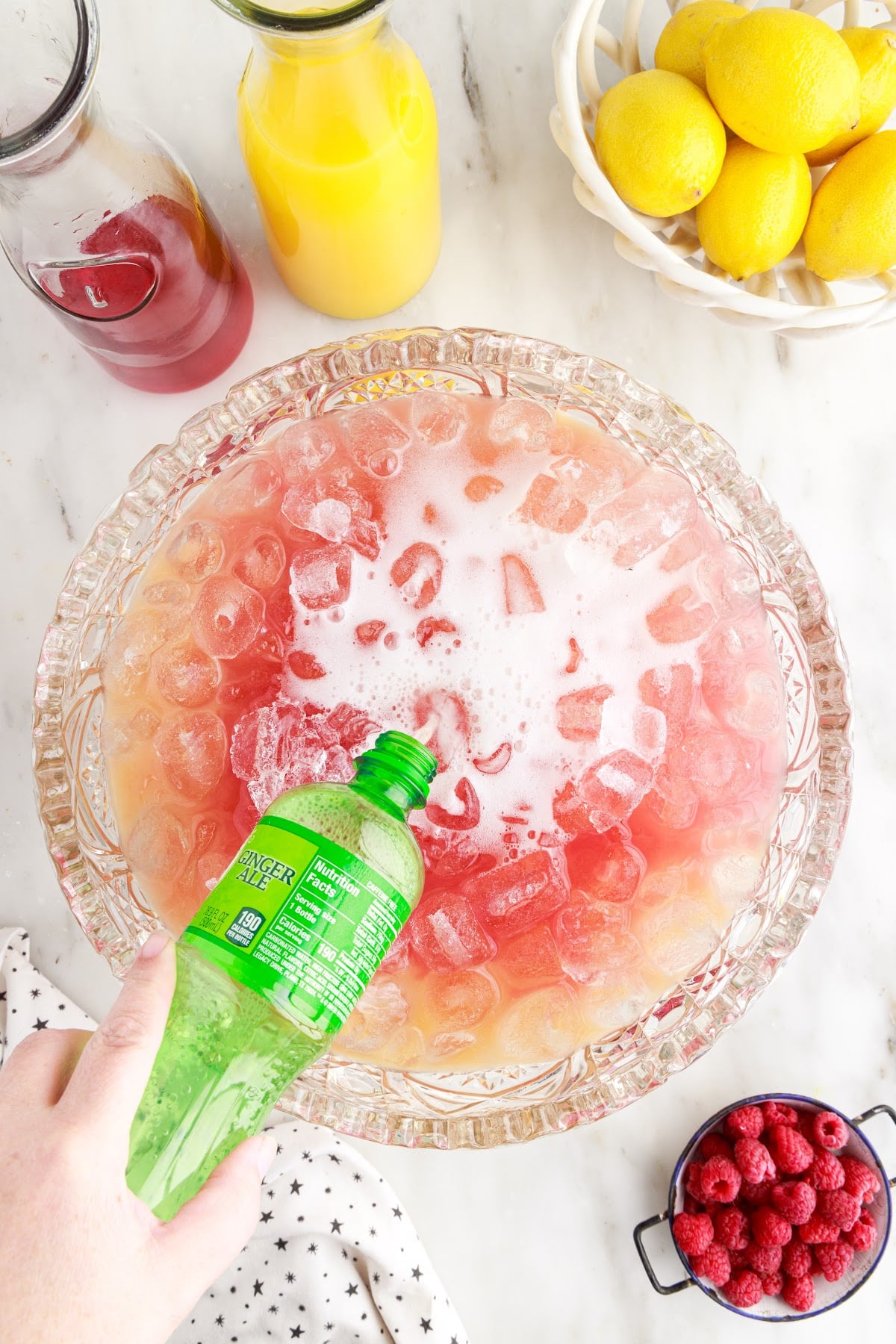 Adding in the soda into the bowl of ice and juice, other ingredients in the background.