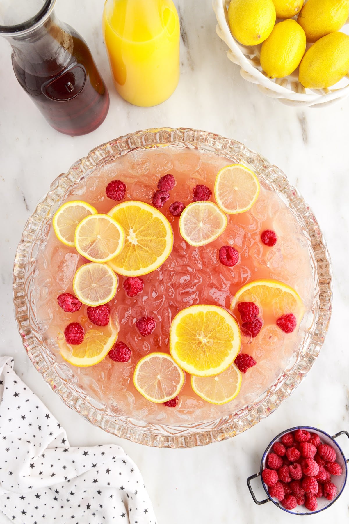 Finished party punch garnished with fresh lemon slices and berries, in a large punch bowl.