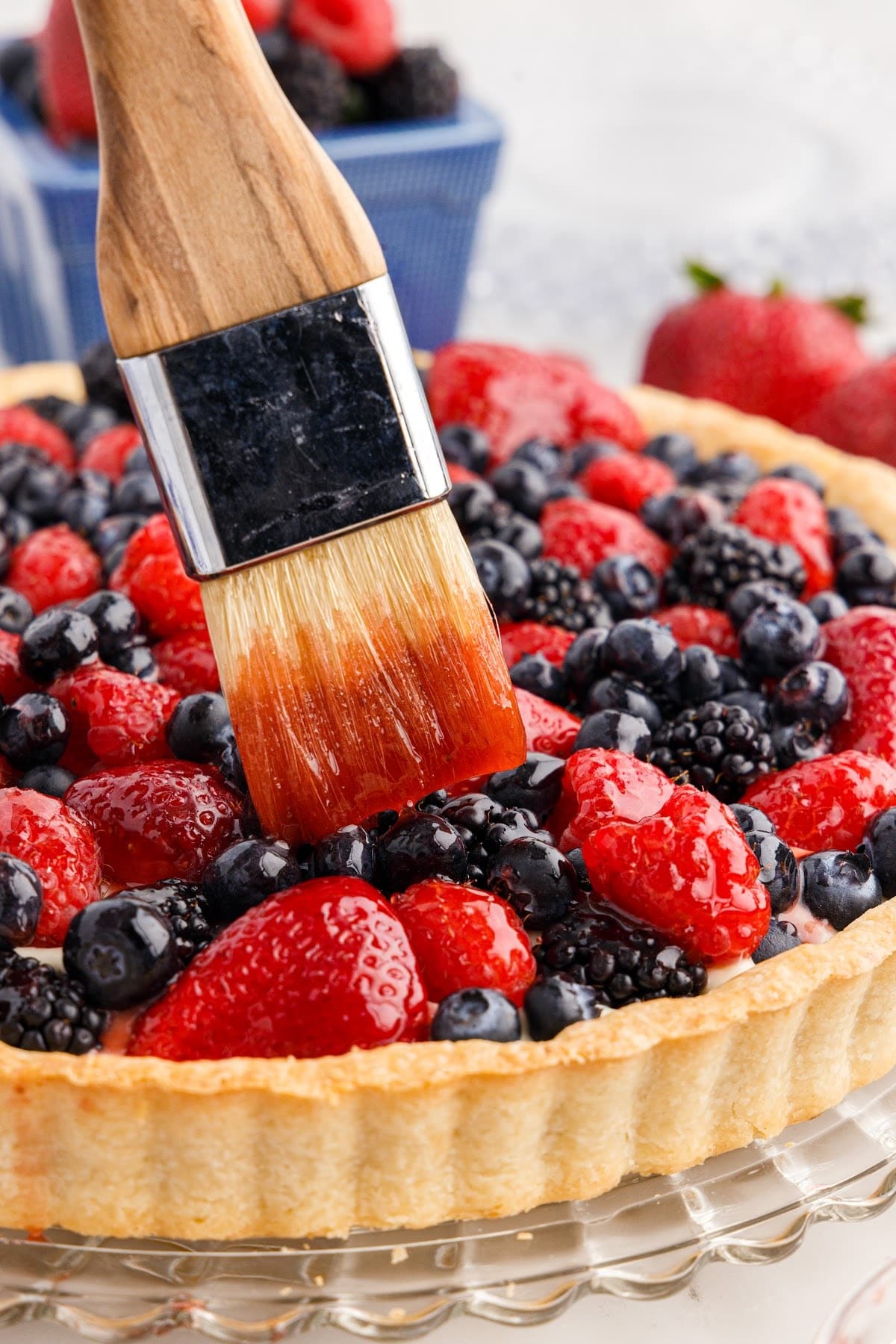 Pastry brush adding a warm jelly glaze to the top of the berries for the Mixed Berry Tart.