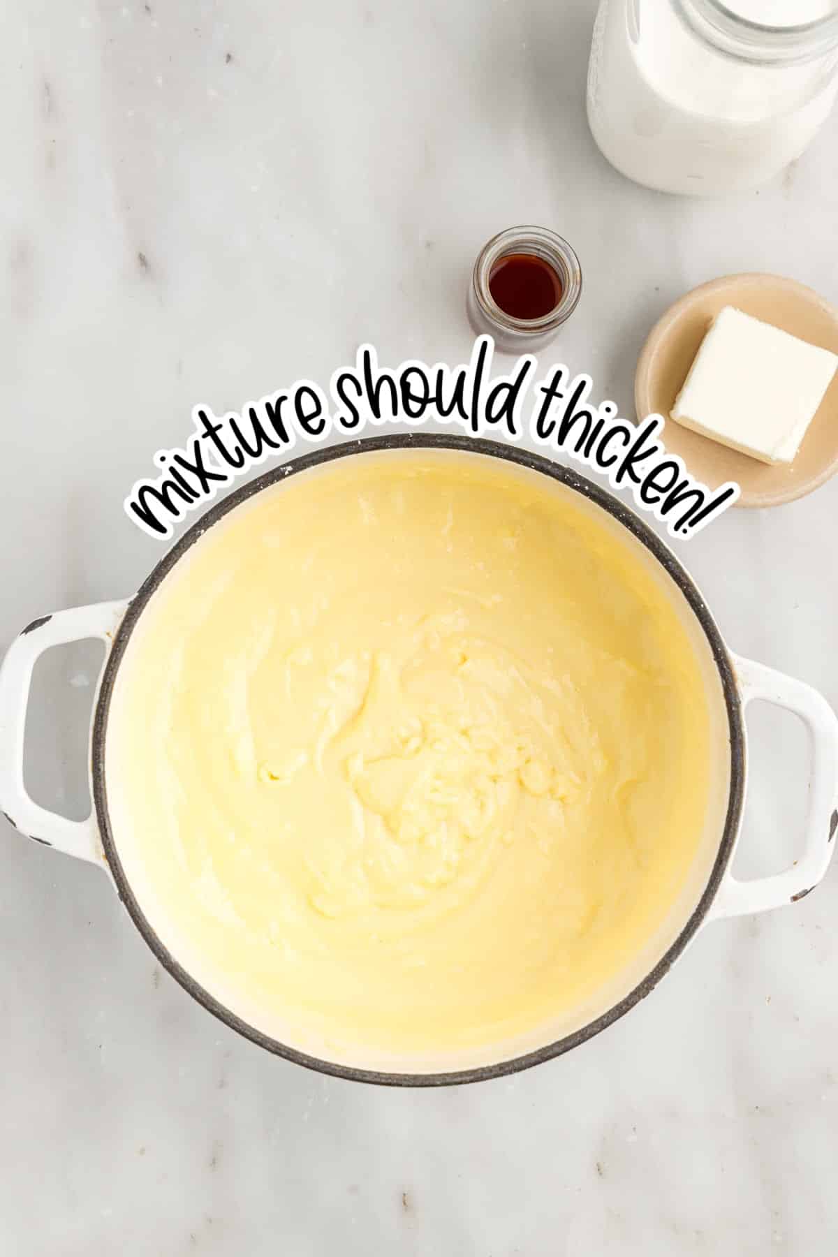 Saucepan with thickened mixture for the Mixed Berry Tart pastry cream. Jug of milk, butter, and vanilla extract set besides the saucepan.