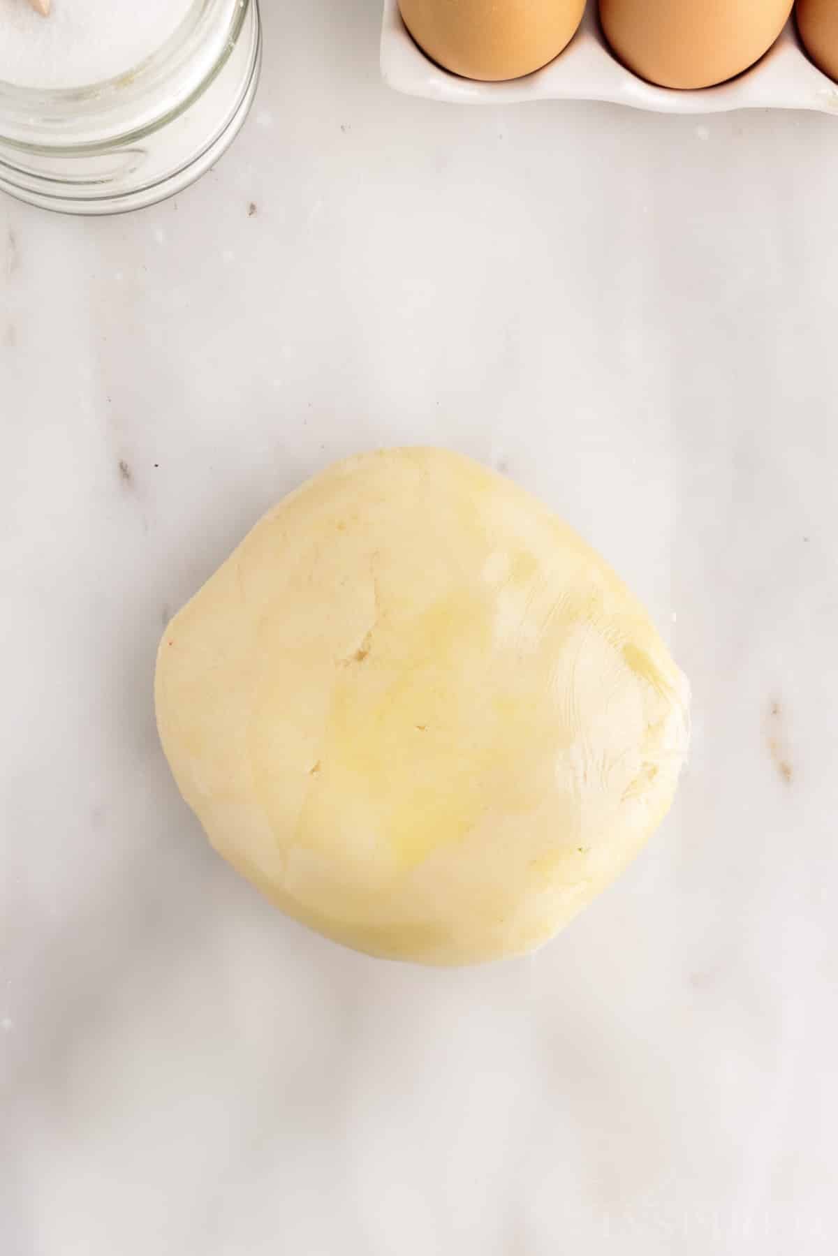 A mound of dough wrapped tightly in plastic wrap.