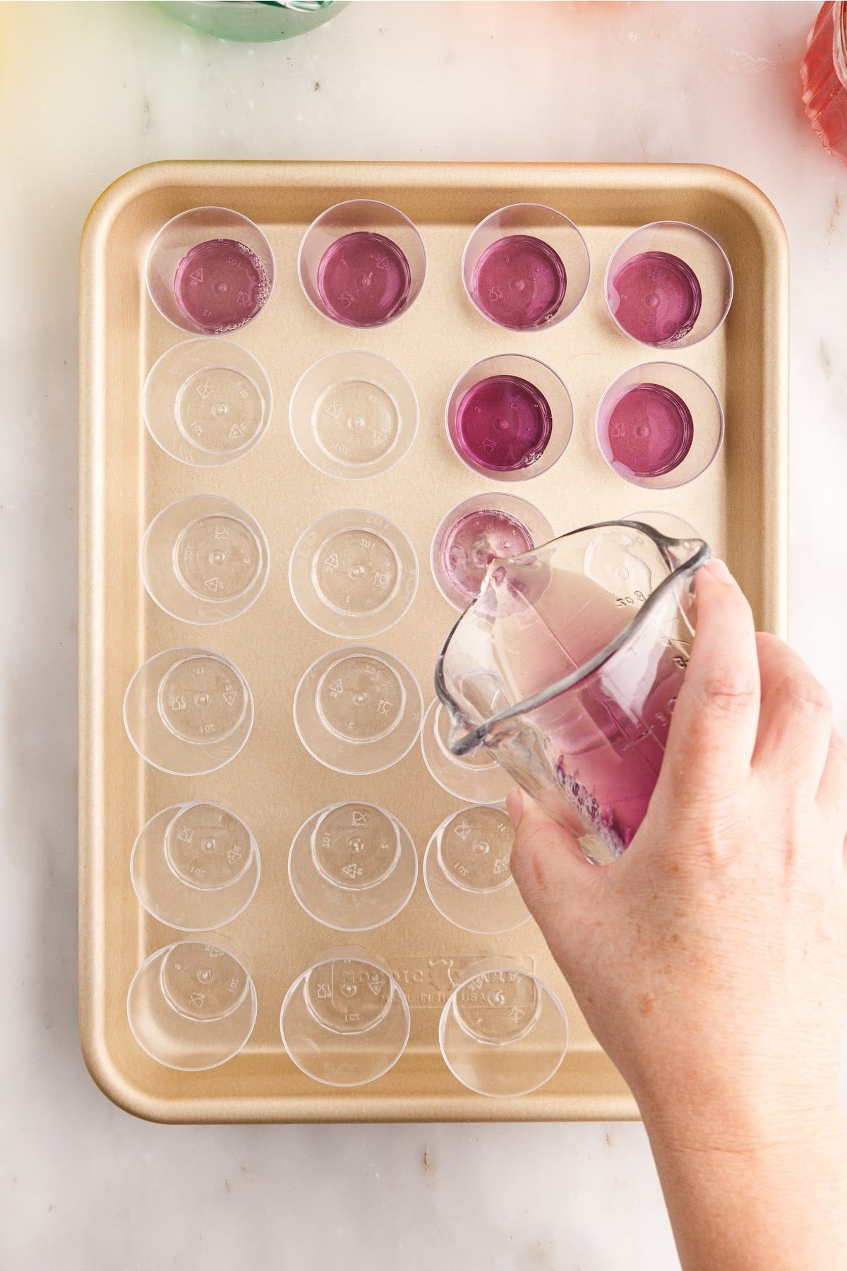 Grape Jello mixture poured into plastic shot glasses on a tray.