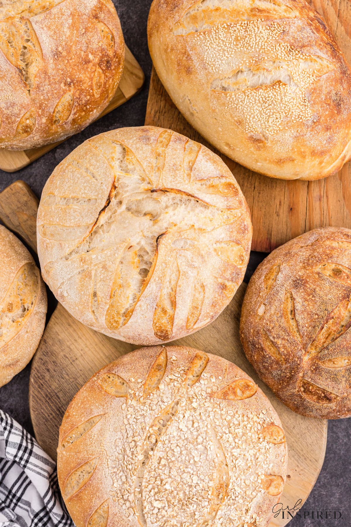 A variety of shaped loaves of sourdough bread set on a bread board.