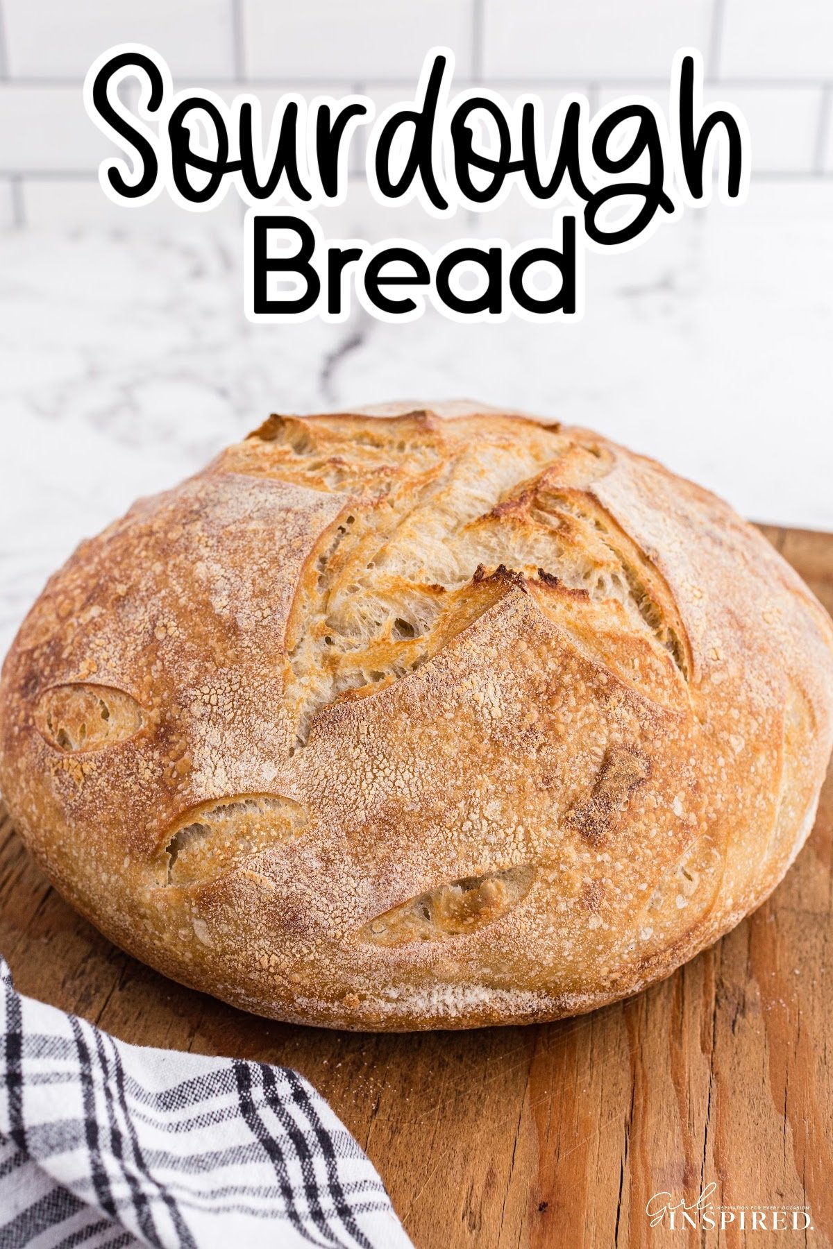 Round loaf of sourdough bread on a cutting board with linen.