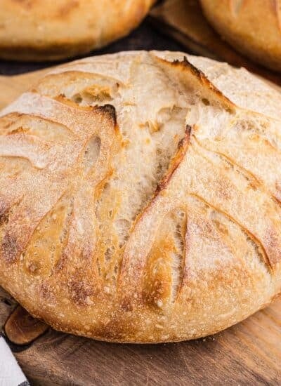 A round loaf of basic sourdough bread on a cutting board.
