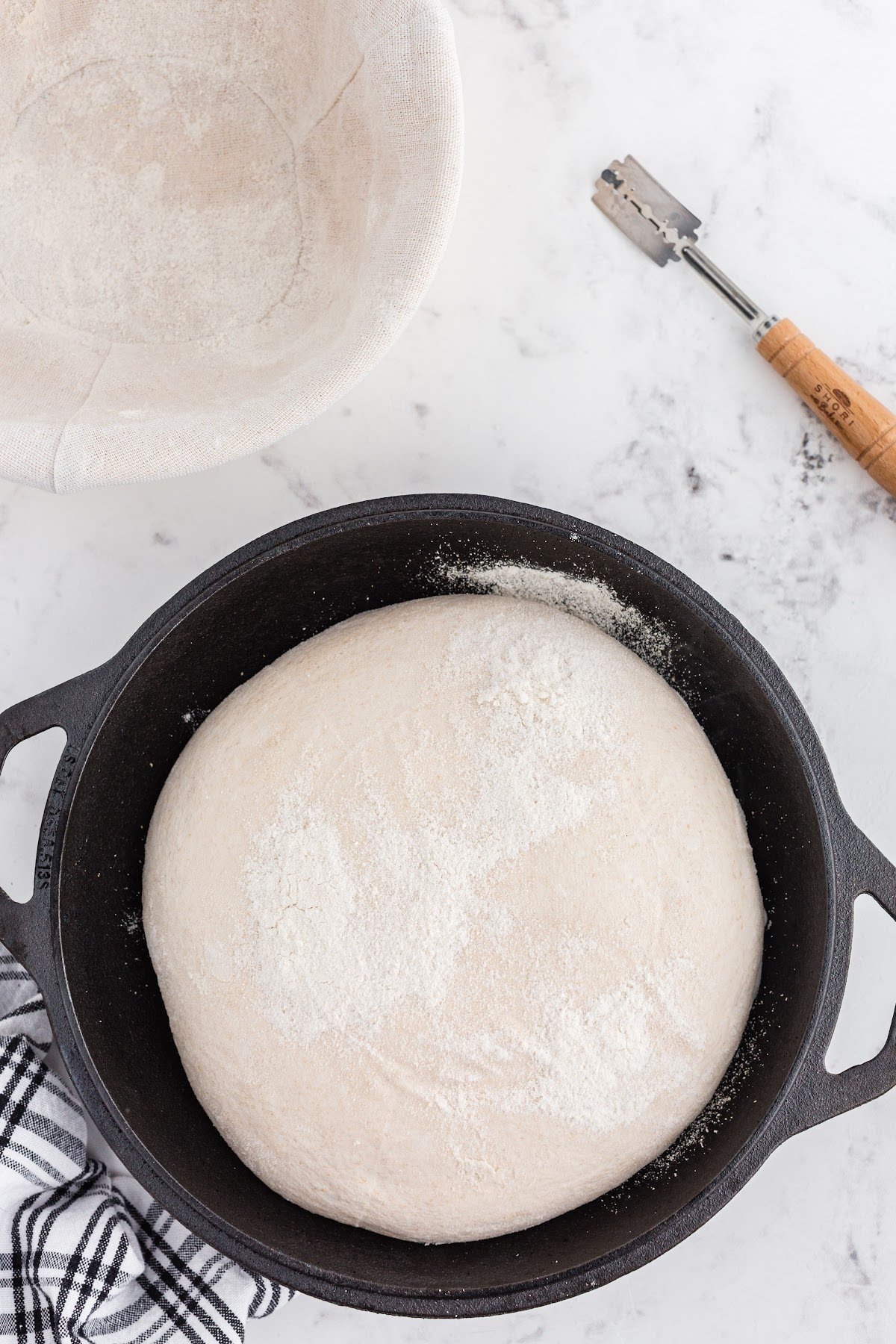 Smooth proofed sourdough loaf in cast iron skillet.