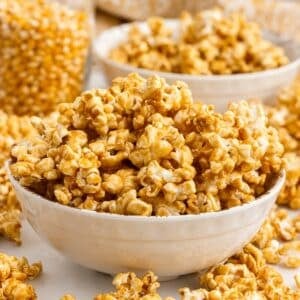 Bowls mounded with caramel corn and a jar of corn kernels in background.