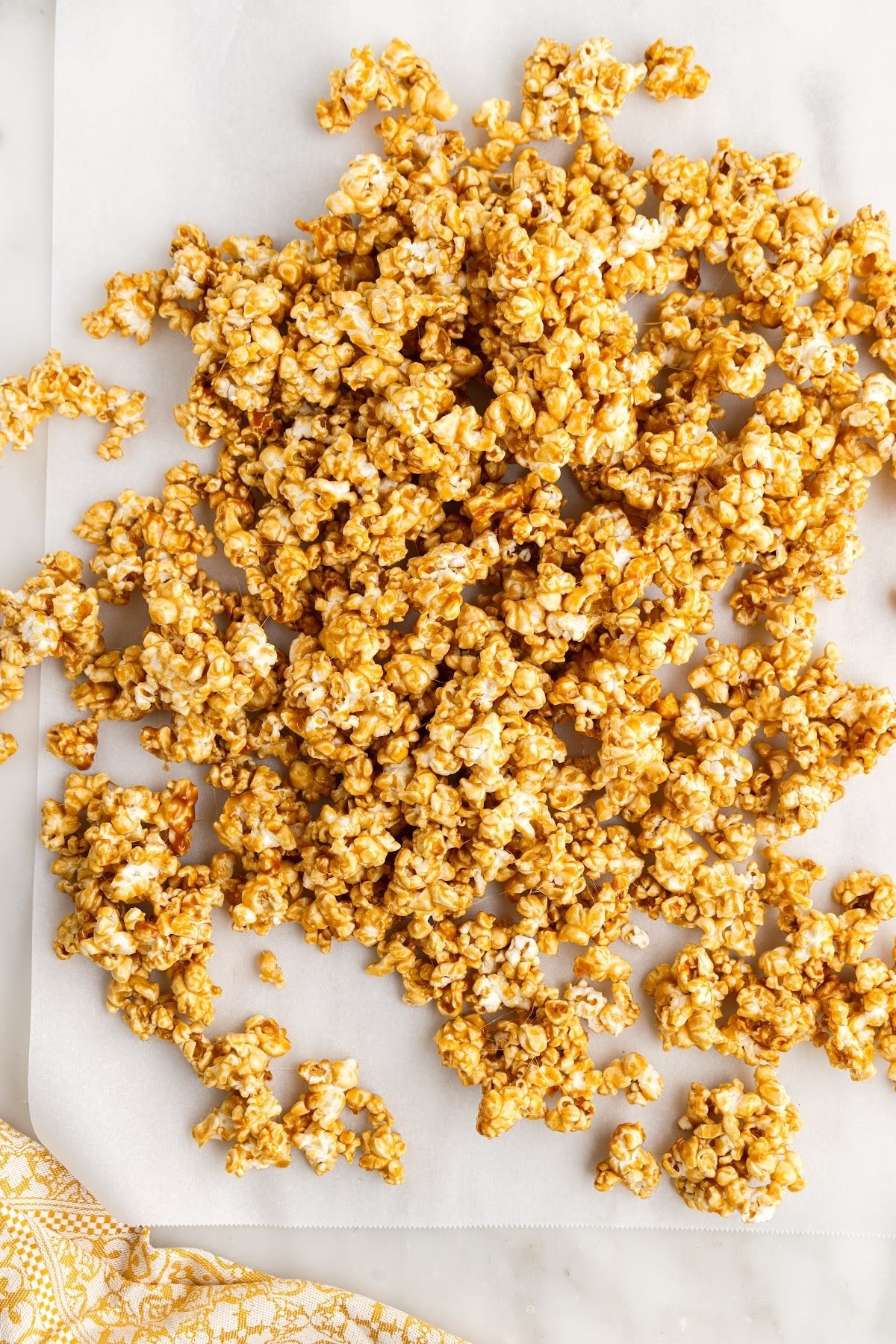 Caramel corn spread out on parchment paper.
