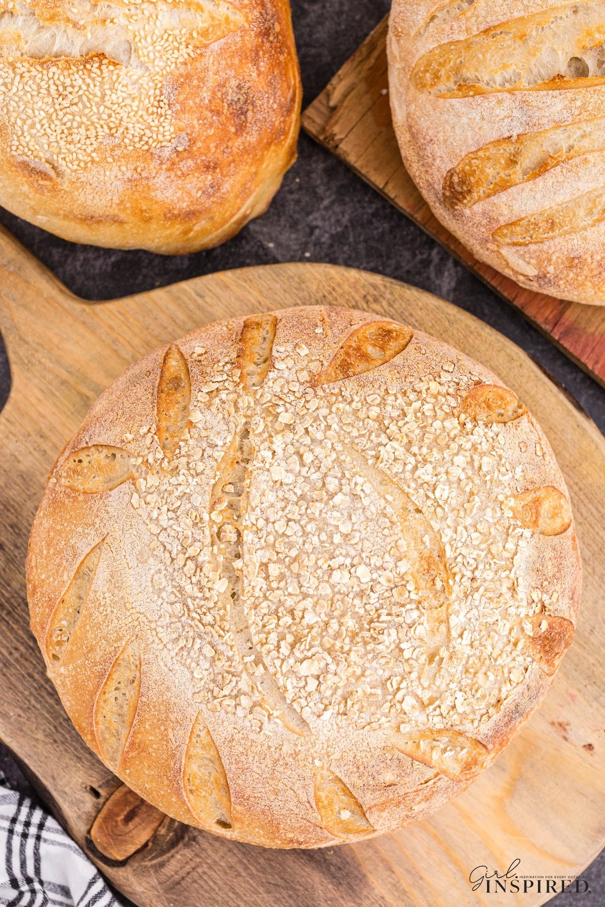 Overhead shot of freshly baked oat sourdough bread on a wooden kitchen board.
