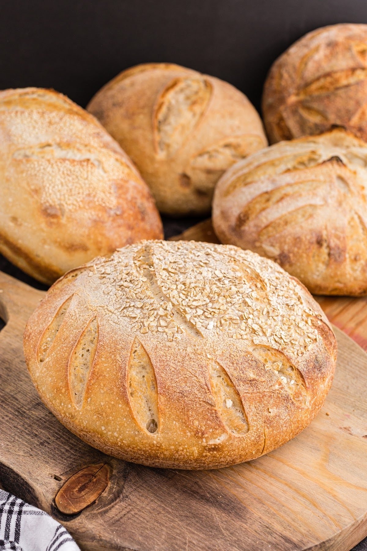 Freshly baked oat sourdough loaves on a wooden kitchen board.