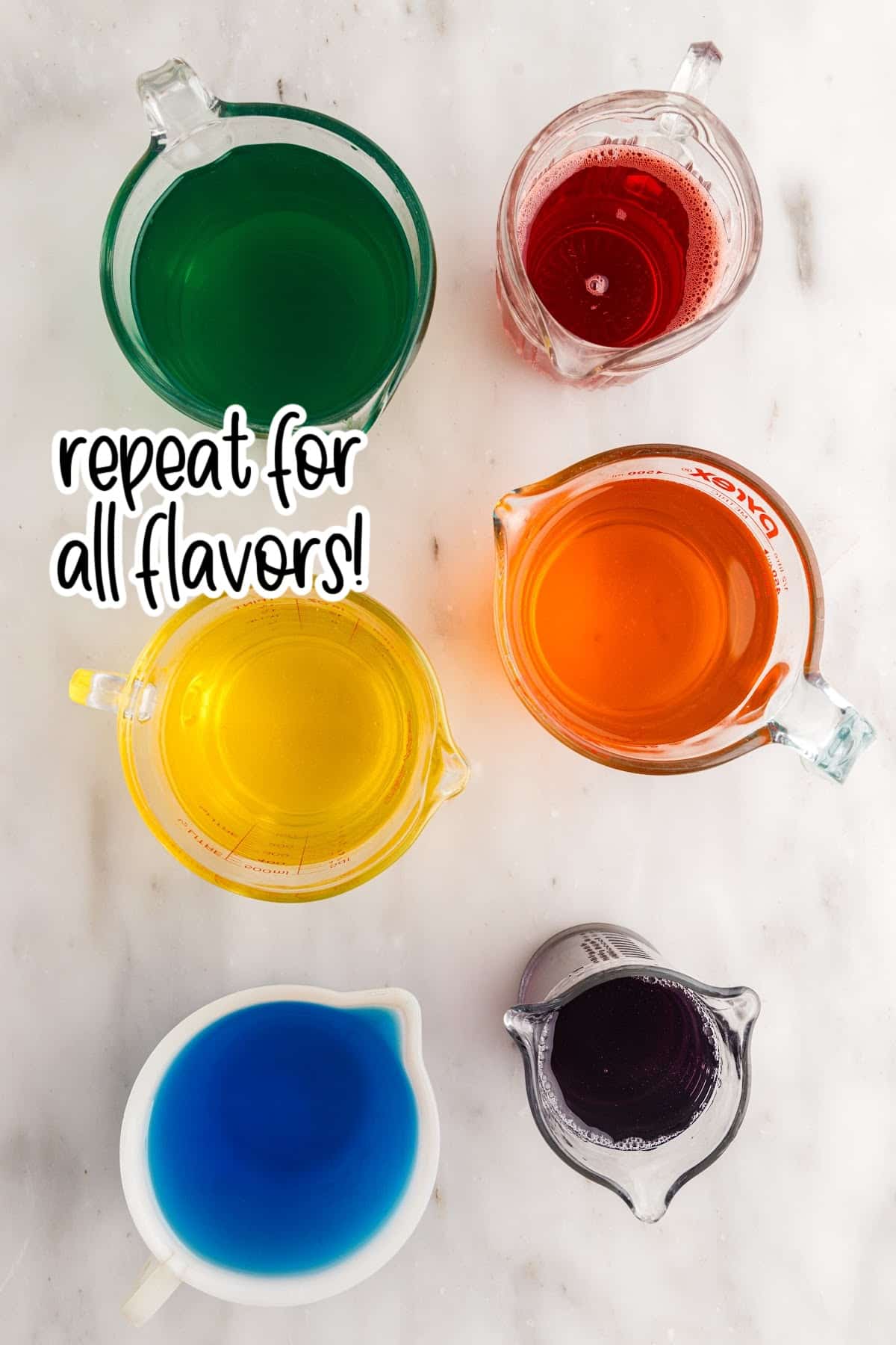 Separate jugs or bowls for each color of dissolved jello, gathered on a marble countertop in preparation for making the rainbow layered jello cups.