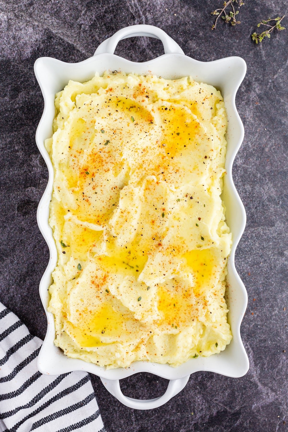 Mashed potato topping spread evenly over the Shepherd's pie topping with a sprinkle of seasonings, fresh thyme, and melted butter poured over.