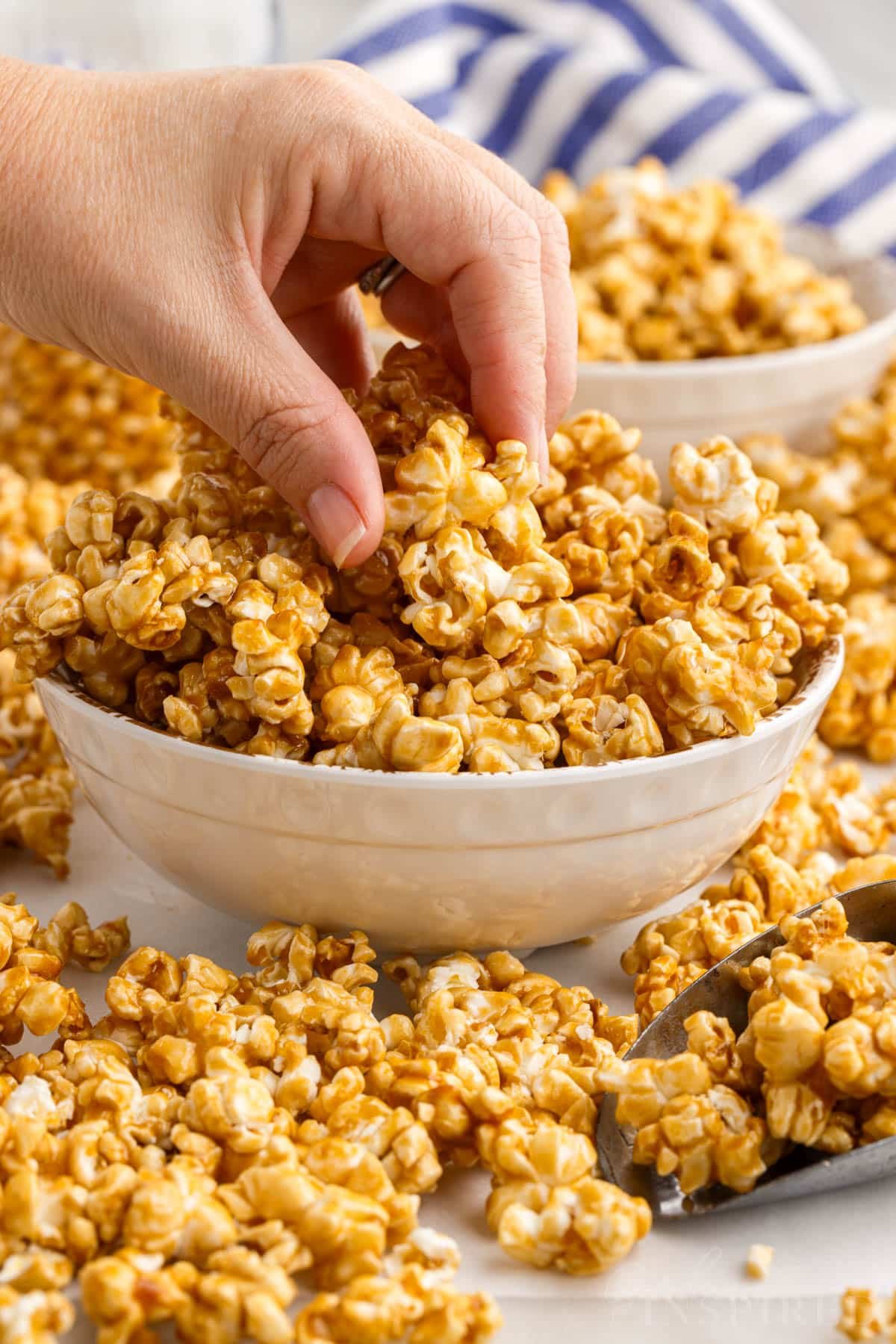 Hand reaching into bowl for a handful of caramel corn.