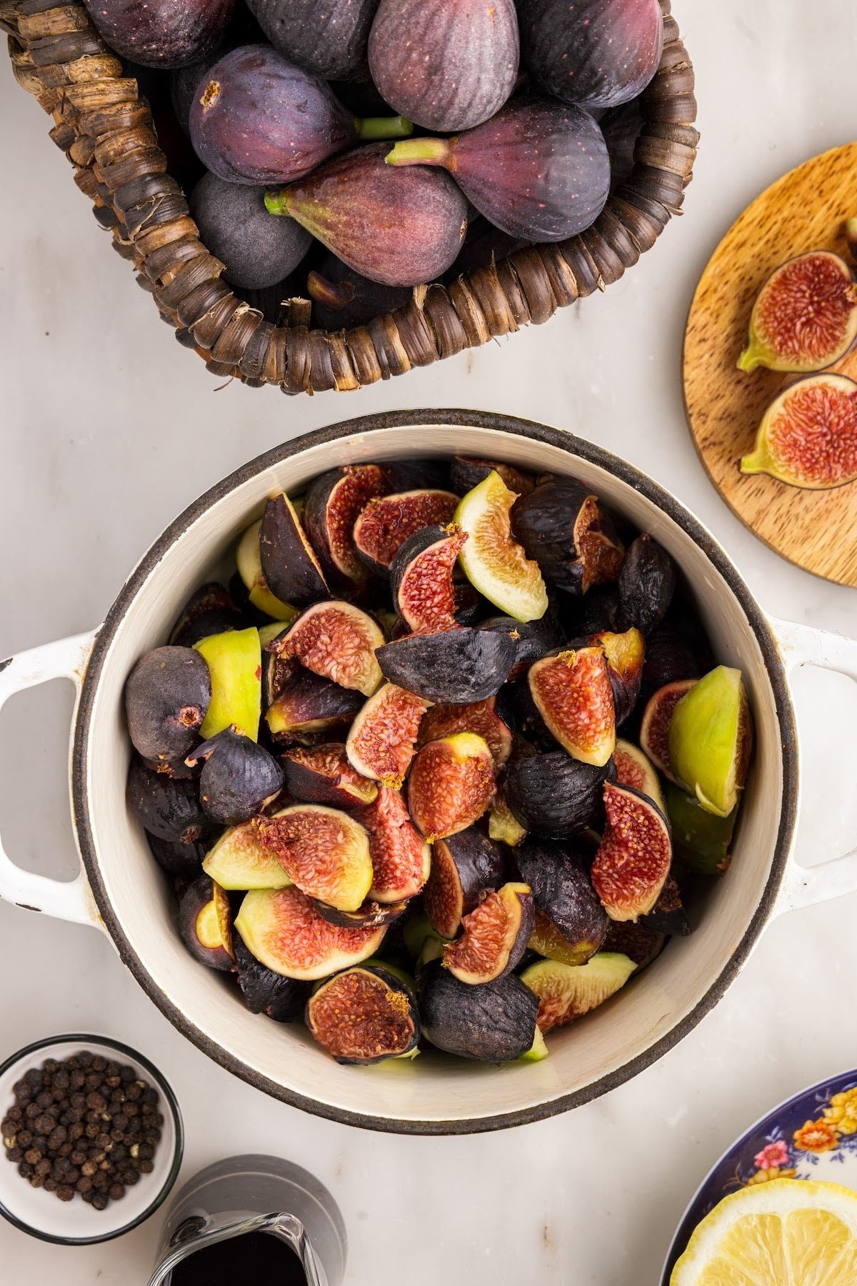 Washed and cut fresh figs in a saucepan. Fresh ingredients in the background.