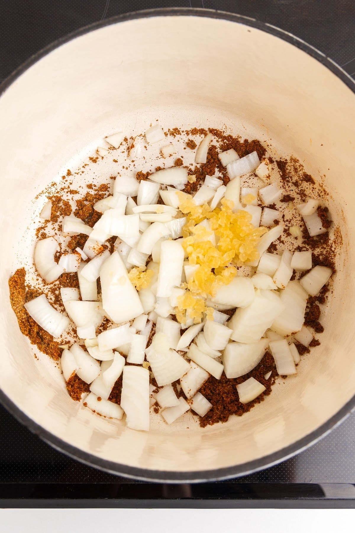 Chopped onion added to the pot of toasted spices for making red enchilada sauce.