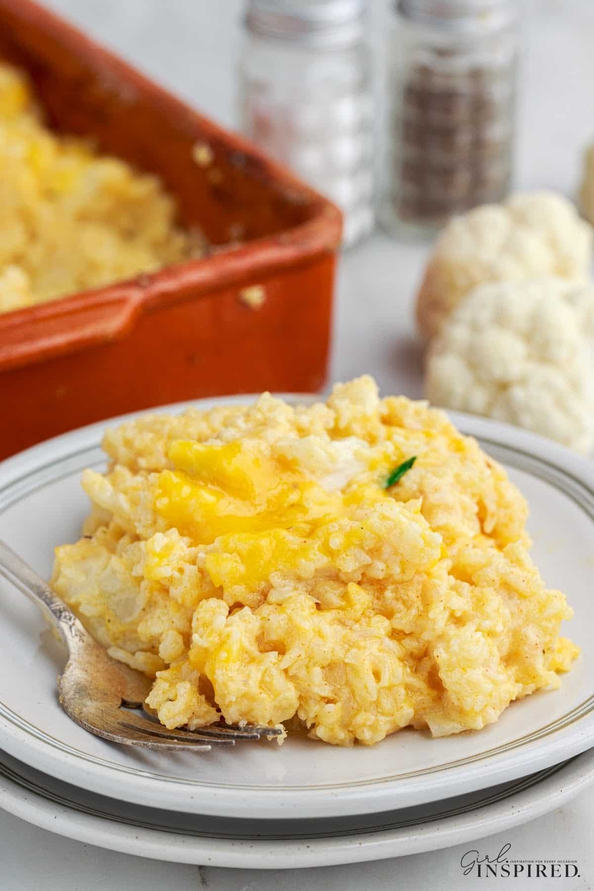 Single serving of vegetarian rice casserole on a white dinner plate with the casserole dish in the background.