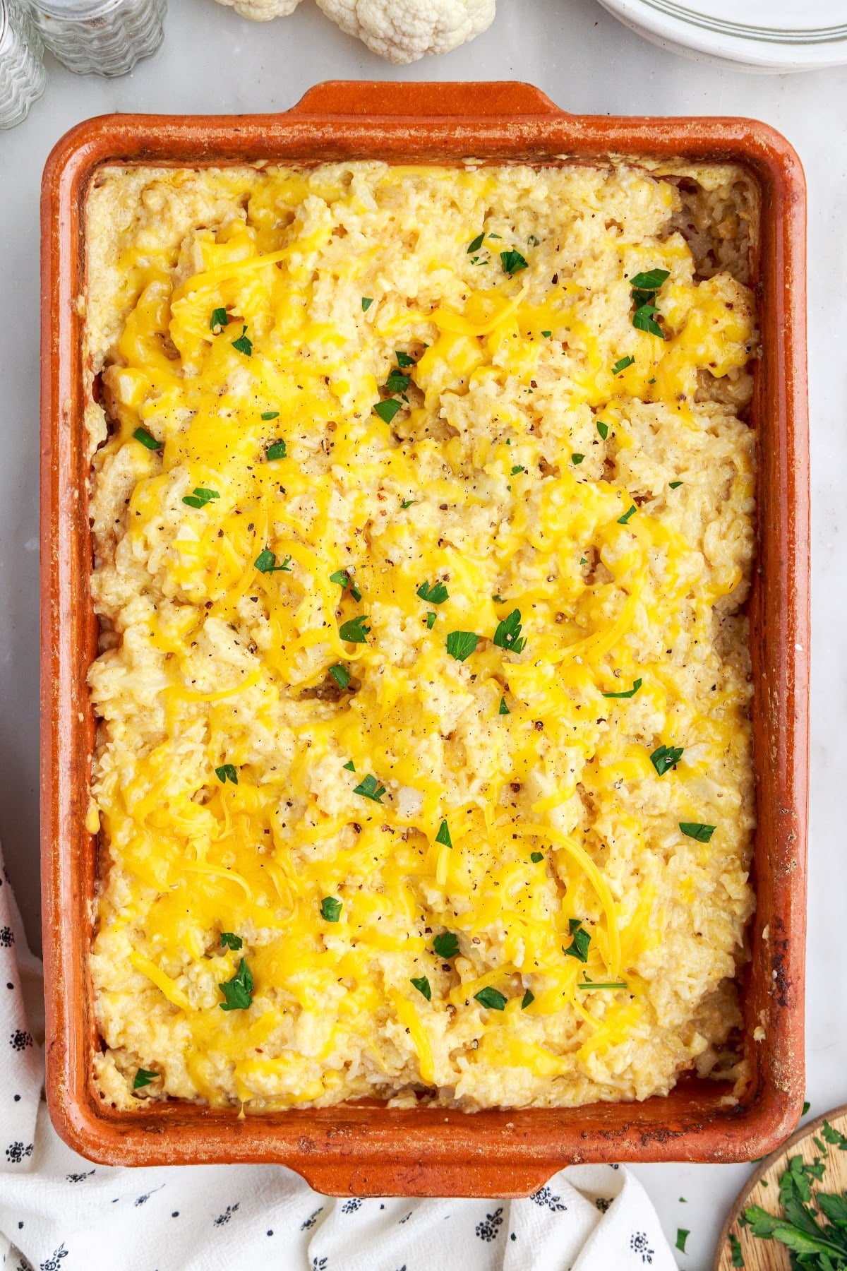 Baked vegetarian rice casserole, topped with cracked black pepper and a sprinkle of chopped parsley.