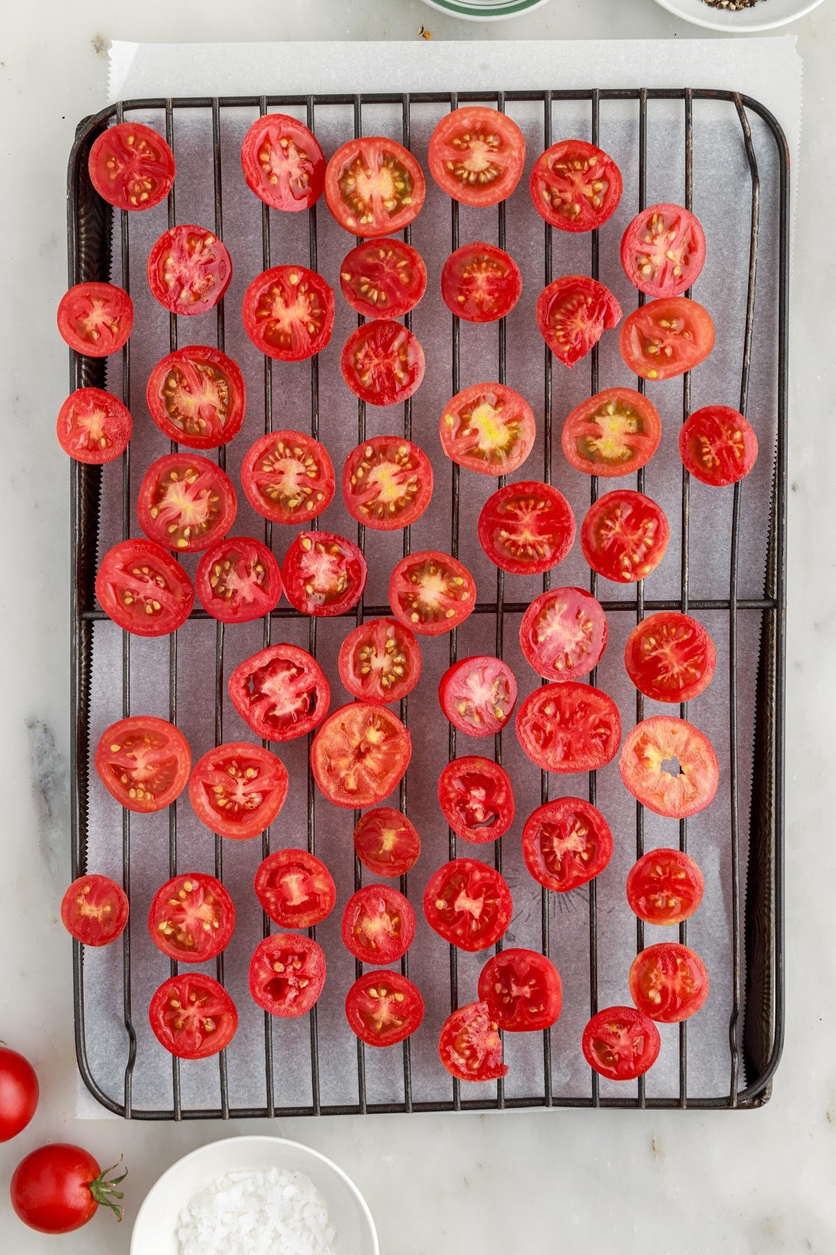 Halved tomatoes on a parchment-lined baking sheet.