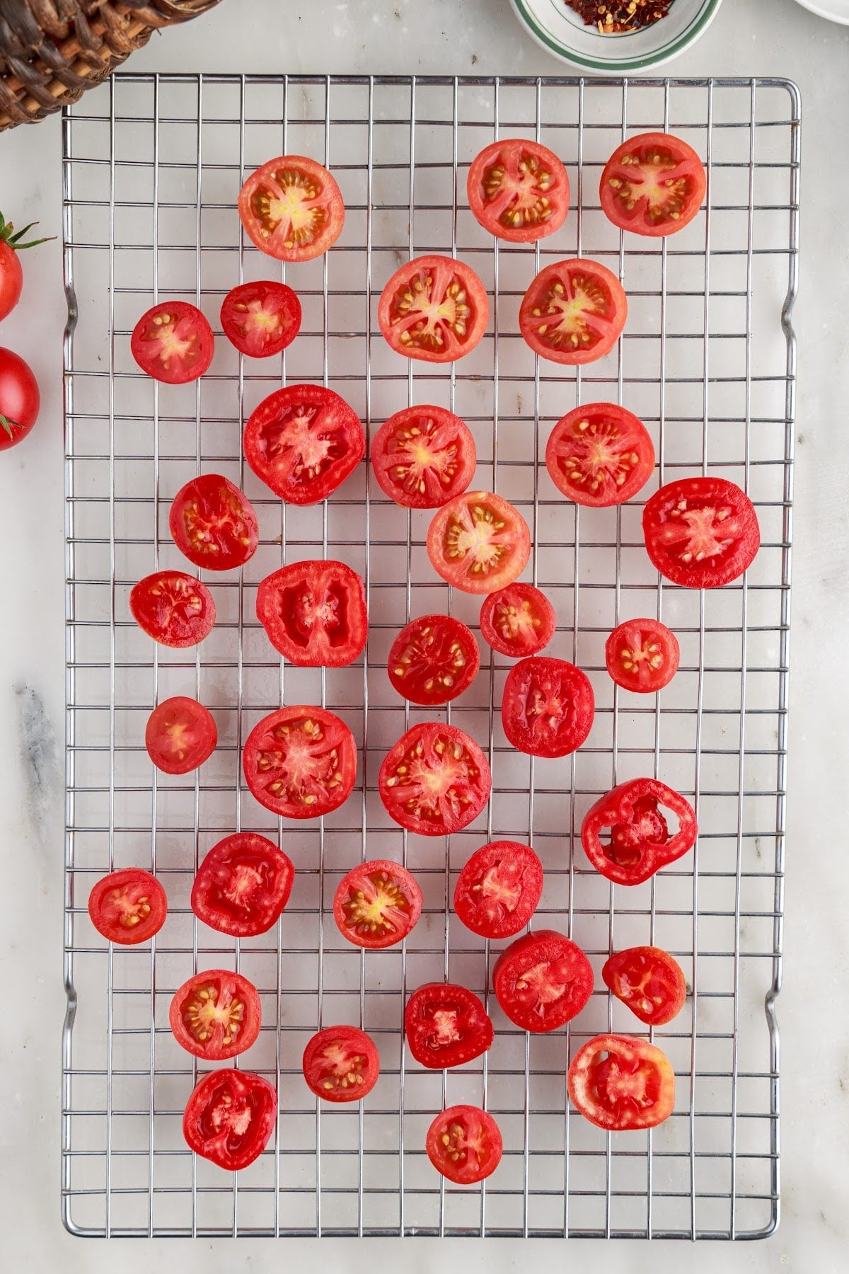 Halved tomatoes on a mesh rack for sun-drying.