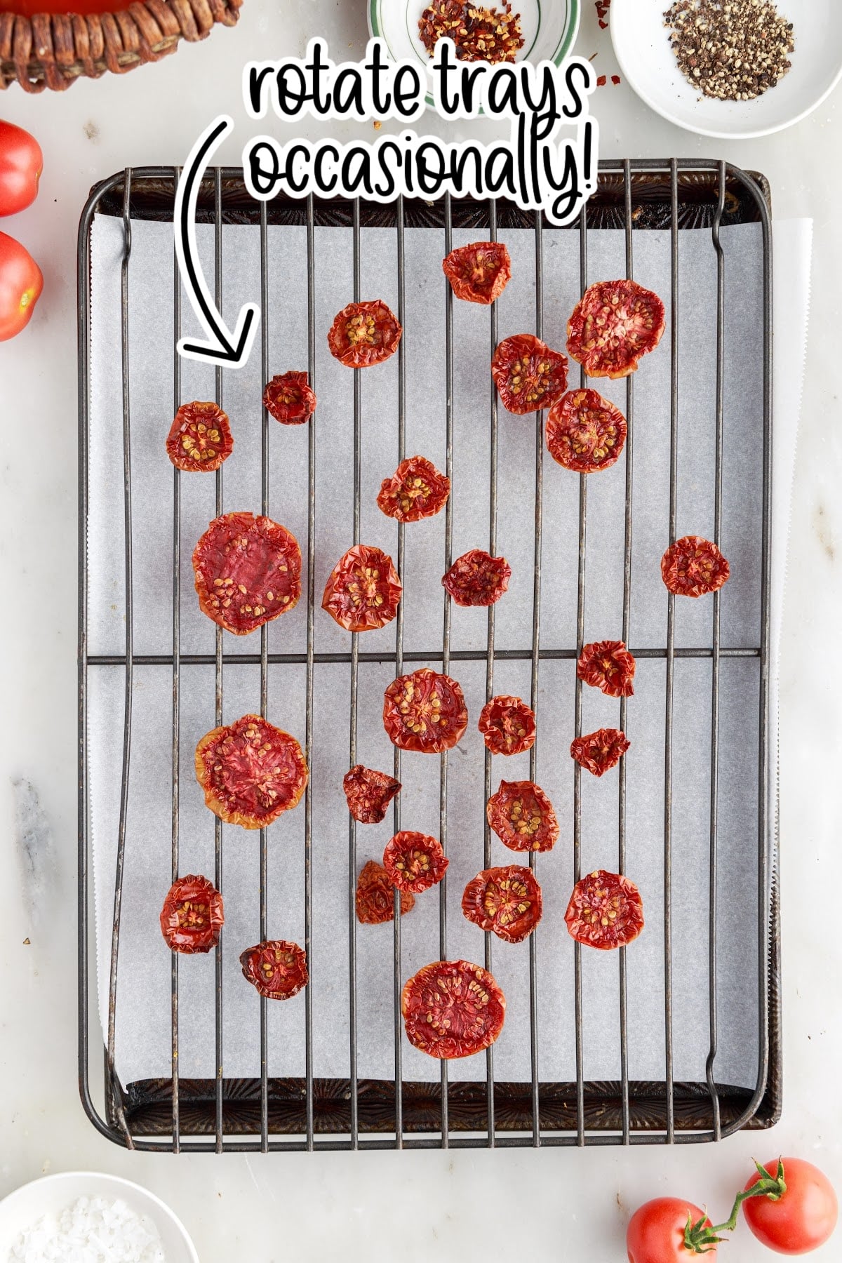 Baked and dried tomatoes on a parchment-lined sheet.