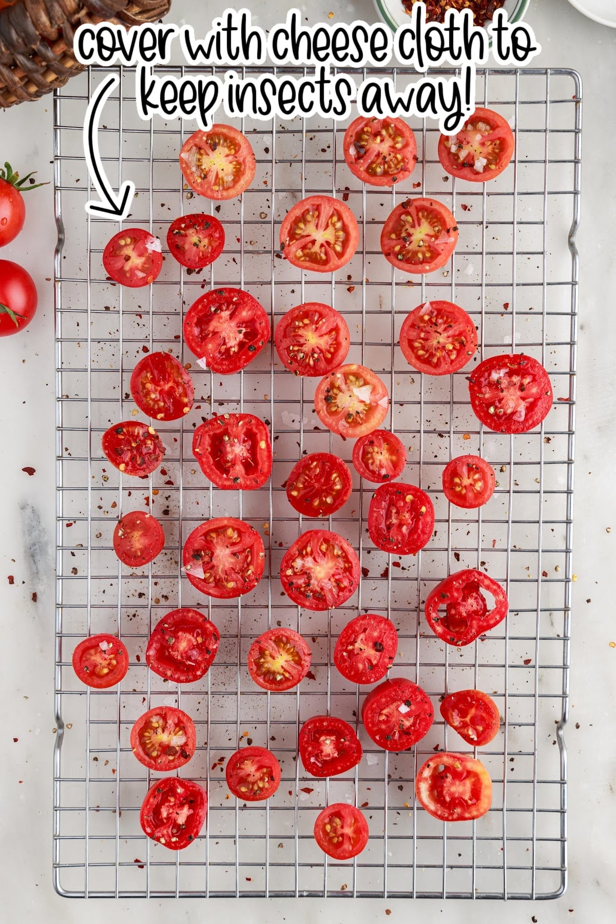 Halved and seasoned tomatoes on a mesh rack.