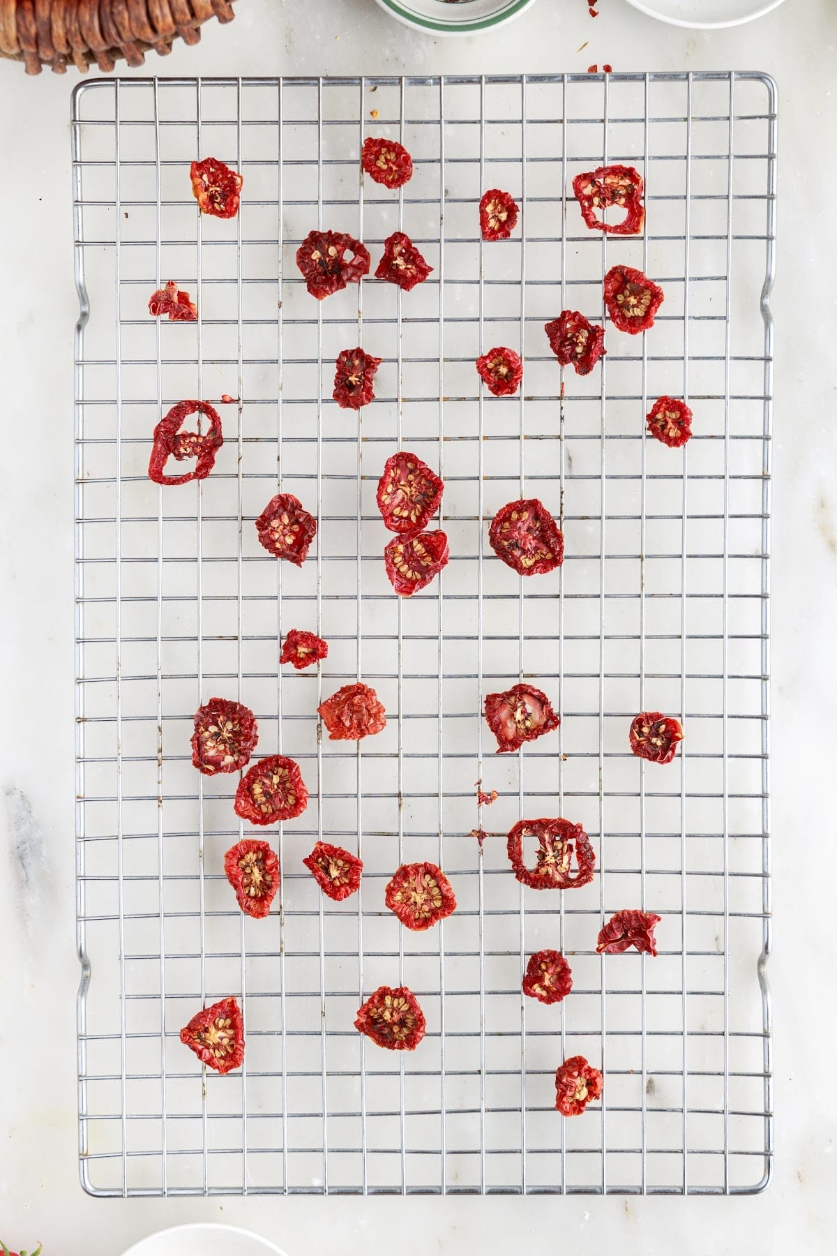 Sun-dried tomatoes that appear leathery and pliable on a mesh rack.