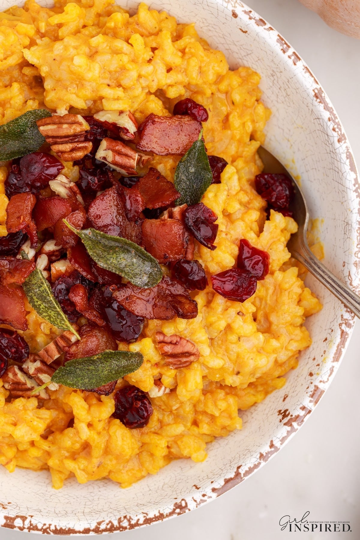 Baked pumpkin risotto with crumbled bacon, fried sage leaves, toasted pecans, and dried cranberries.