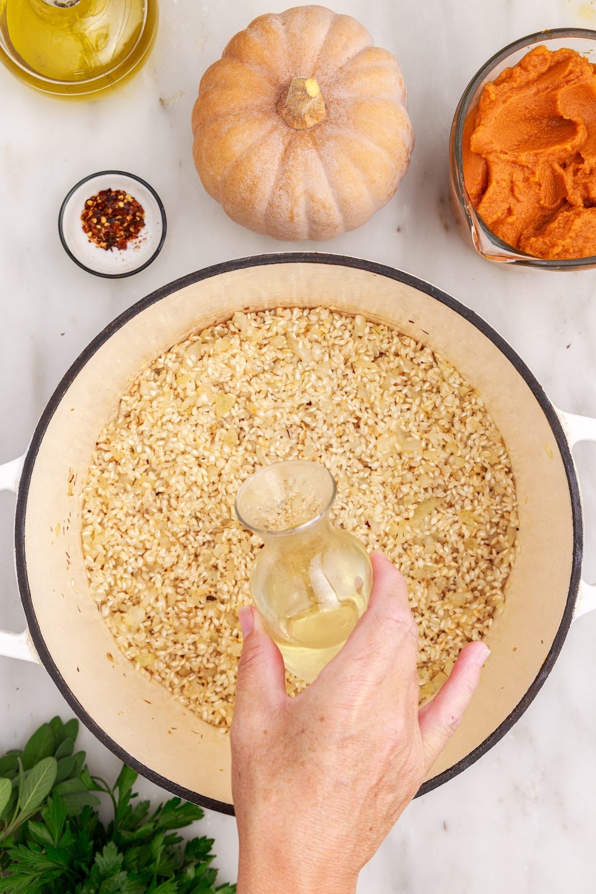 White wine poured into a Dutch oven with other ingredients for making baked pumpkin risotto.